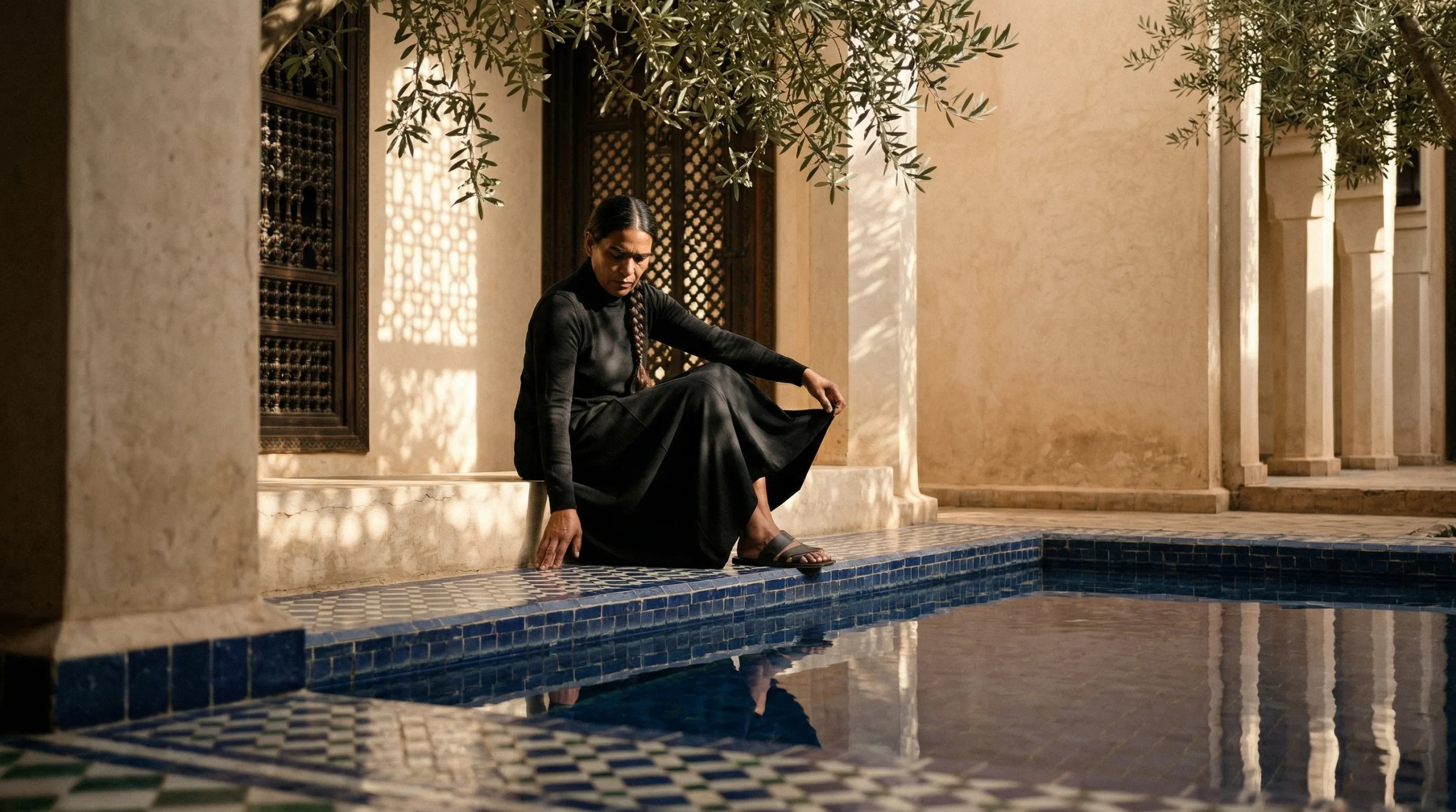Shoot 002 — the Berber riad. A striking Berber woman seated at the edge of the tiled reflecting pool, olive branches and a soft-focus arch framing the shot. Six-block stack, first try. This shoot was the unnoticed control group for everything that came after.